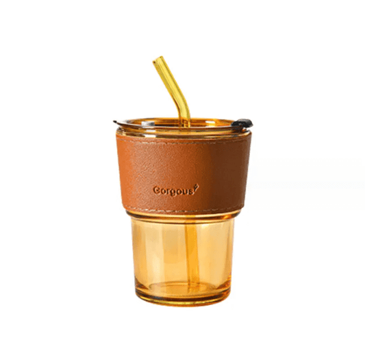 Stylish amber glass coffee cup with a leather sleeve and golden straw, perfect for elegant sipping moments.